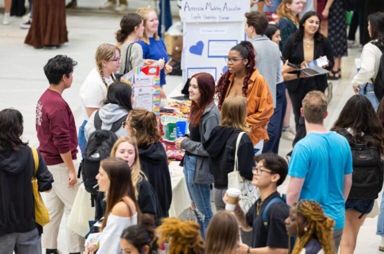 Students collaborating on campus crowdsourcing community projects using laptops, posters, and shared tools to solve local issues.